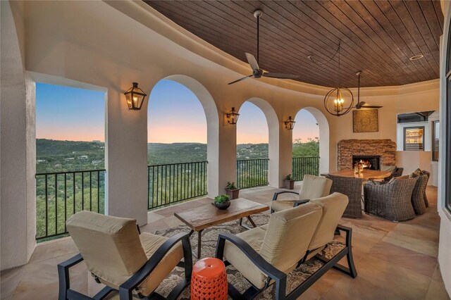 1710 Mount Larson Rd, Austin, TX 78746 - patio terrace at dusk with an outdoor living space with a fireplace, a ceiling fan, and a patio