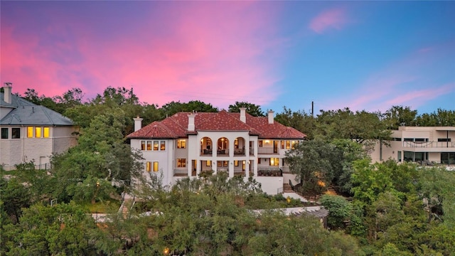 1710 Mount Larson Rd, Austin, TX 78746 - back of property at dusk featuring a balcony, a chimney, and stucco siding