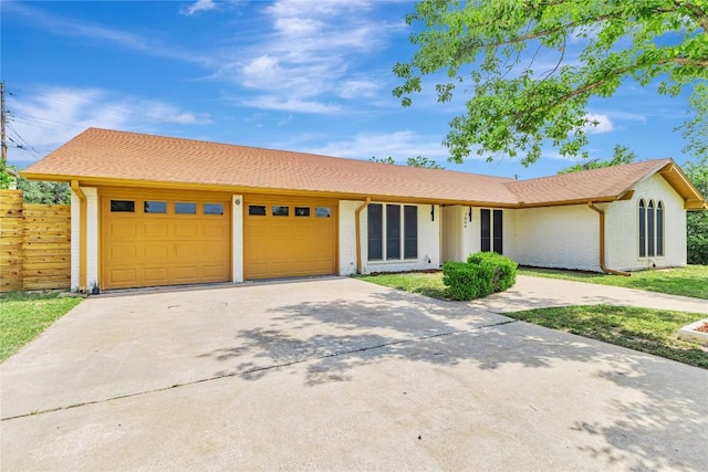view of front of home featuring an attached garage, concrete driveway, brick siding, and fence