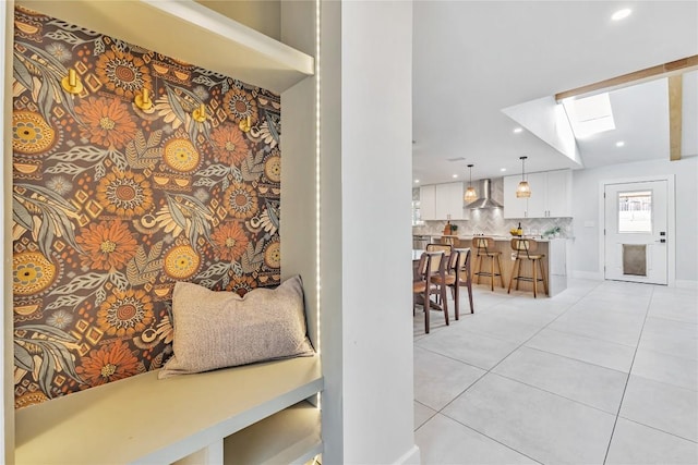 hall featuring a skylight, light tile patterned floors, and recessed lighting