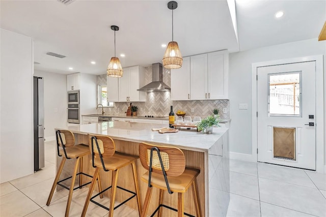 kitchen with wall chimney exhaust hood, light tile patterned floors, backsplash, stainless steel appliances, and recessed lighting