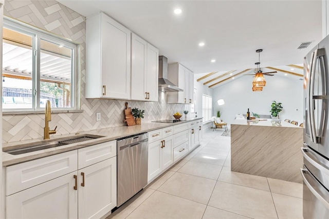 kitchen with stainless steel appliances, wall chimney range hood, a sink, backsplash, and white cabinetry