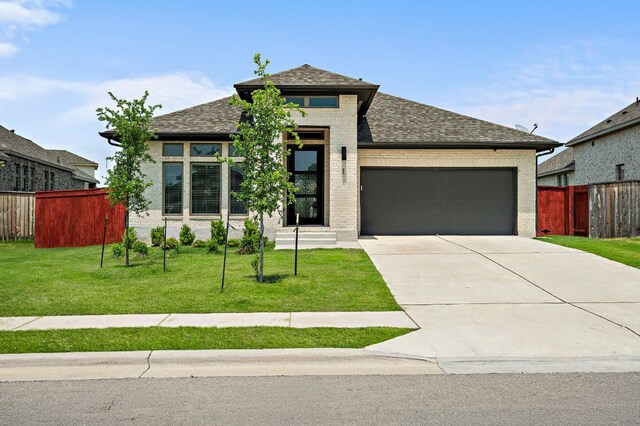 14505 Kira Ln, Manor, TX 78653 - view of front of property featuring an attached garage, driveway, brick siding, and a shingled roof