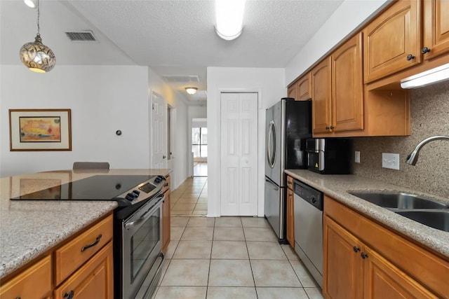 8807 Honeysuckle Trl, Austin, TX 78759 - kitchen with stainless steel appliances, a sink, light tile patterned floors, tasteful backsplash, and brown cabinets