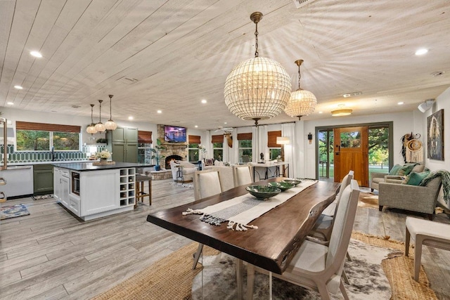 dining room with light wood-type flooring, a chandelier, recessed lighting, wooden ceiling, and a fireplace