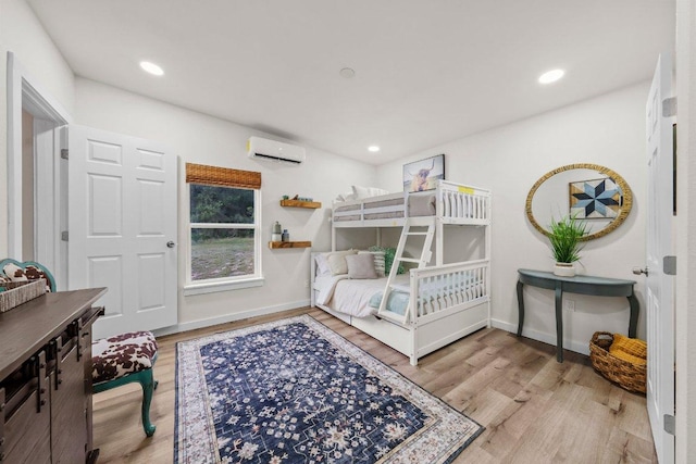 bedroom featuring an AC wall unit, wood finished floors, baseboards, and recessed lighting