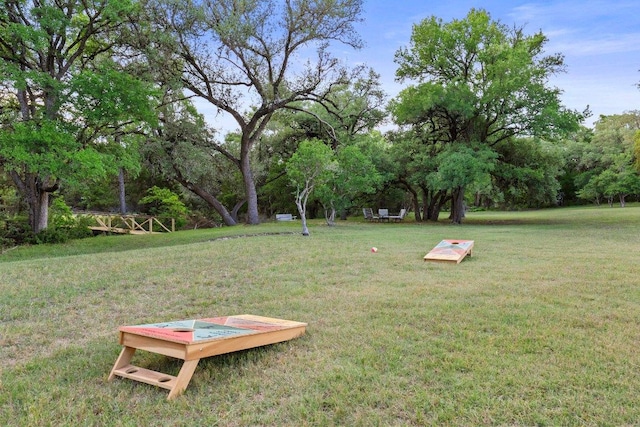 view of green lawn featuring view of wooded area
