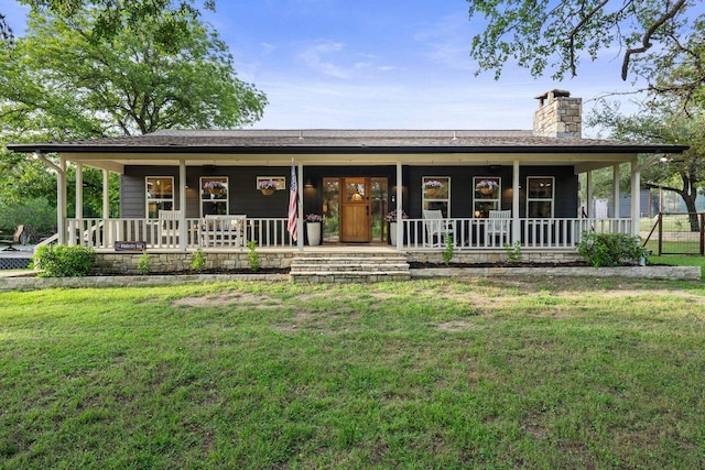 view of front of property featuring covered porch, a chimney, and a front lawn