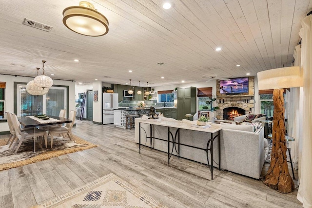 living area featuring wooden ceiling, light wood-style flooring, recessed lighting, a chandelier, and a fireplace