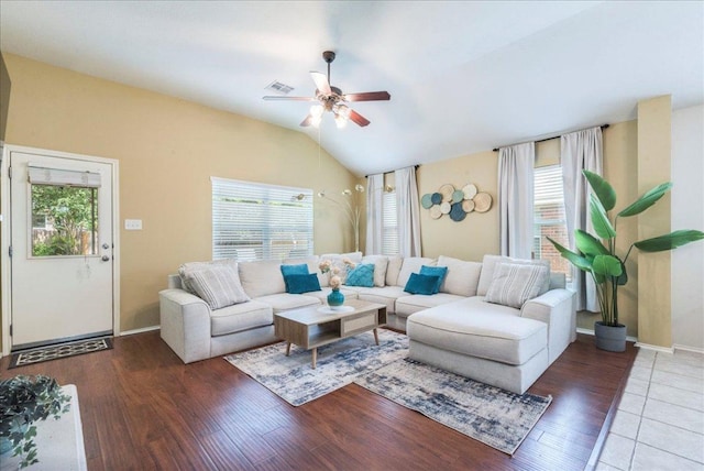 living area featuring healthy amount of natural light, a ceiling fan, wood finished floors, vaulted ceiling, and baseboards