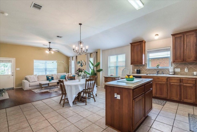 kitchen with vaulted ceiling, open floor plan, light countertops, tasteful backsplash, and brown cabinets