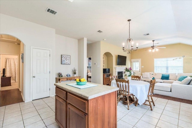 kitchen with light tile patterned flooring, open floor plan, arched walkways, hanging light fixtures, and light countertops