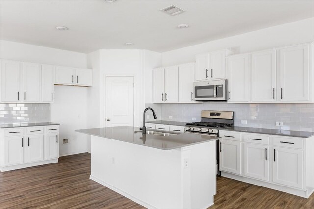 1203 Diggy Dr, Austin, TX 78748 - kitchen with appliances with stainless steel finishes, decorative backsplash, dark wood-style flooring, a kitchen island with sink, and white cabinets