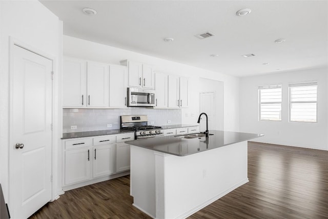 1203 Diggy Dr, Austin, TX 78748 - kitchen featuring appliances with stainless steel finishes, a sink, dark wood-style flooring, a center island with sink, and tasteful backsplash