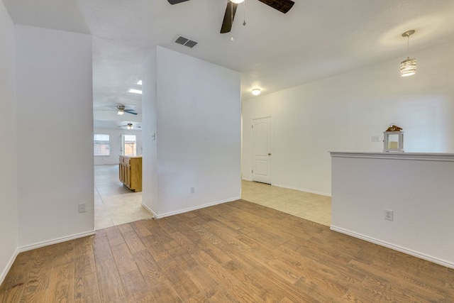 spare room with a ceiling fan, light wood-style flooring, and baseboards