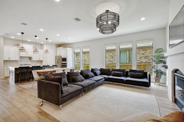 living room featuring light wood-type flooring, recessed lighting, and a chandelier