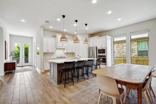 kitchen with appliances with stainless steel finishes, a center island with sink, light countertops, a breakfast bar, and white cabinets