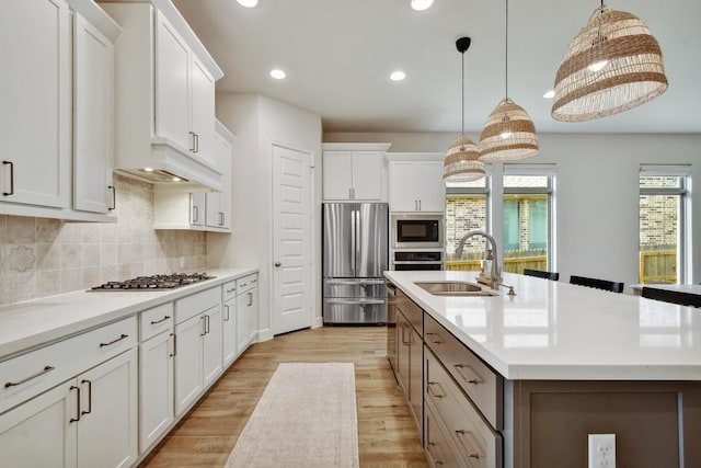 kitchen featuring stainless steel appliances, a sink, recessed lighting, a center island with sink, and tasteful backsplash