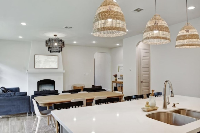 kitchen featuring a sink, arched walkways, recessed lighting, light countertops, and decorative light fixtures