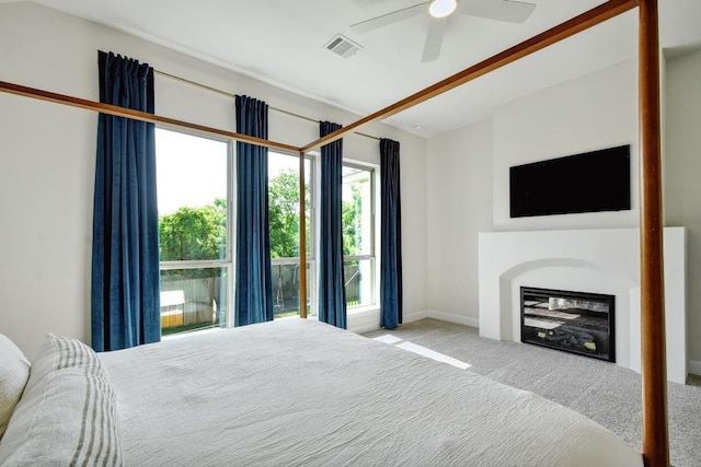 bedroom with carpet flooring, a glass covered fireplace, a ceiling fan, and baseboards