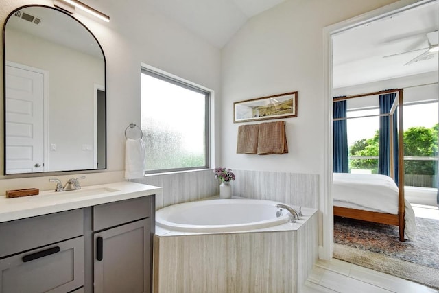 ensuite bathroom with vanity, a garden tub, lofted ceiling, and tile patterned floors