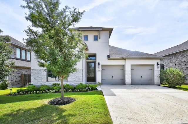 modern home featuring a garage, driveway, a front lawn, stone siding, and roof with shingles