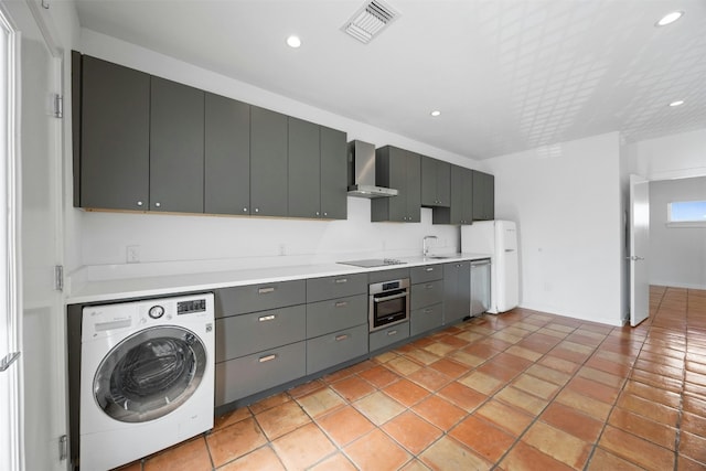 kitchen featuring washer / clothes dryer, appliances with stainless steel finishes, wall chimney range hood, light countertops, and recessed lighting