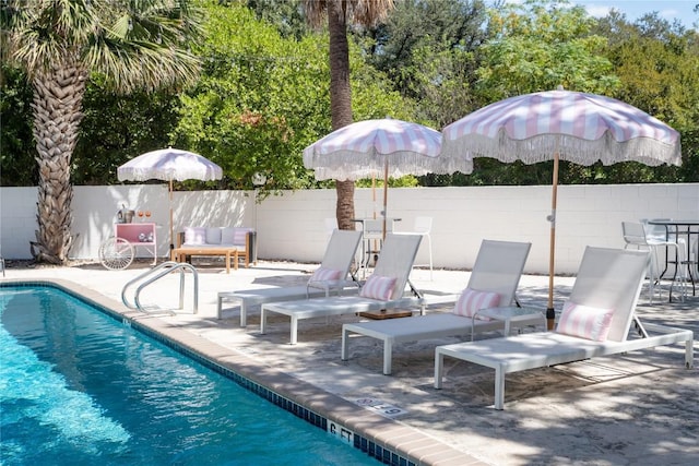 view of swimming pool featuring a patio and fence