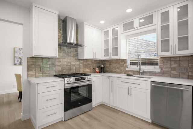 9127 Edwardson Ln, Austin, TX 78749 - kitchen with stainless steel appliances, wall chimney exhaust hood, light countertops, white cabinets, and light wood-style floors