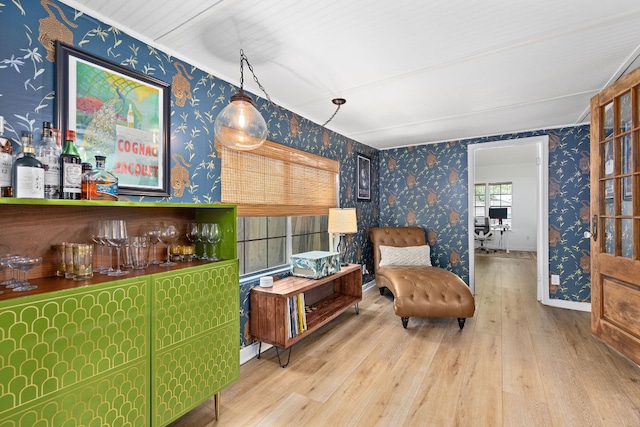sitting room featuring wallpapered walls, a bar, and wood finished floors