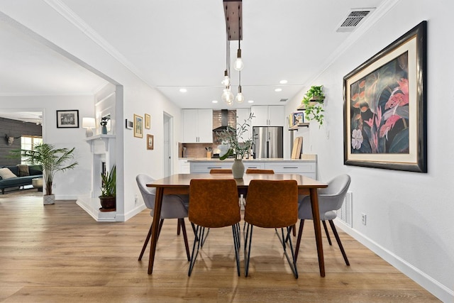 dining area with ornamental molding, light wood-style floors, baseboards, and recessed lighting