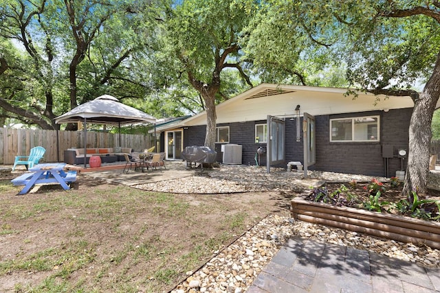 back of house with fence, a patio, brick siding, central AC unit, and an outdoor living space