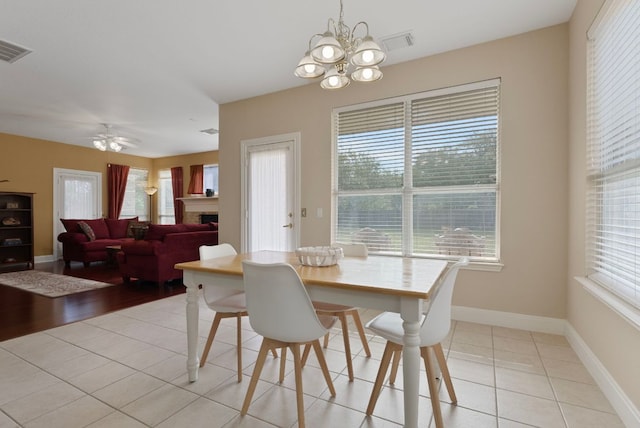 8105 Red Bird Ct, Austin, TX 78726 - dining space with a chandelier, a fireplace, light tile patterned flooring, and ceiling fan