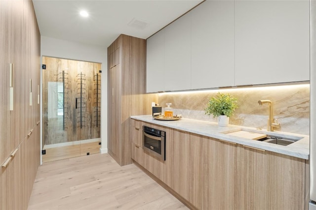 kitchen featuring modern cabinets, a sink, oven, and tasteful backsplash