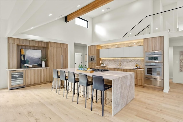 620 Bermuda St, Lakeway, TX 78734 - kitchen featuring beverage cooler, modern cabinets, a warming drawer, high vaulted ceiling, and a breakfast bar area