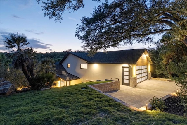 view of home's exterior with stucco siding, a lawn, an attached garage, and concrete driveway