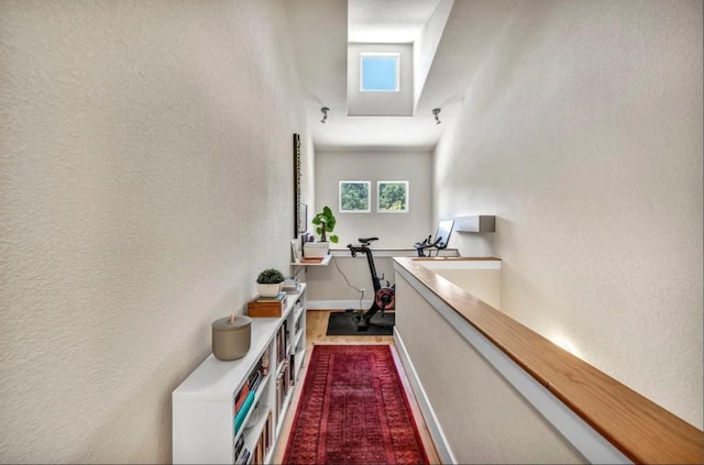 hallway with a textured wall and baseboards