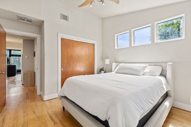 bedroom with baseboards, light wood-type flooring, a closet, and a ceiling fan
