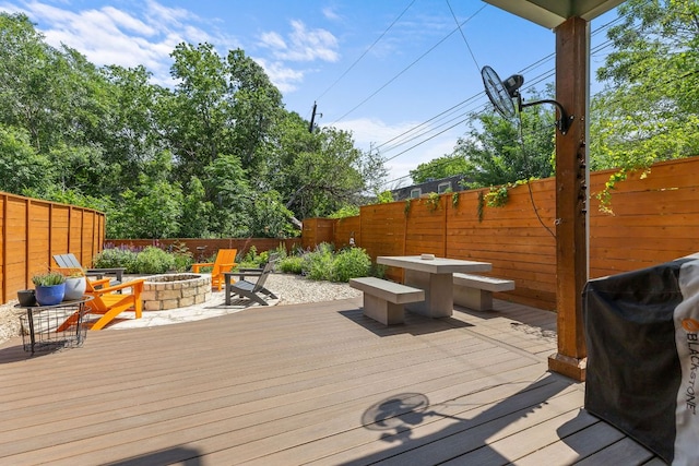 deck with an outdoor fire pit, a fenced backyard, and area for grilling