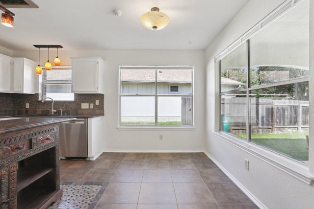 2912 Sydney Dr, Austin, TX 78728 - kitchen with stainless steel dishwasher, dark countertops, white cabinetry, decorative backsplash, and pendant lighting