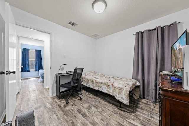 607 Big Bend Trl, Taylor, TX 76574 - bedroom featuring wood finished floors, an office area, and a textured ceiling