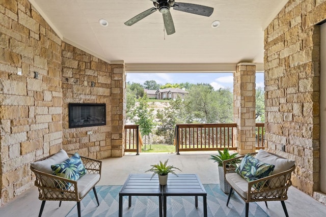 view of patio with an outdoor living space with a fireplace and ceiling fan