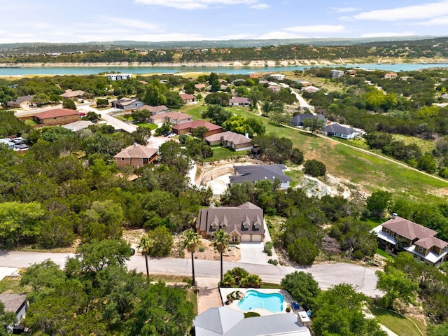 aerial view of residential area with a large body of water, a pool area, and a tree filled landscape