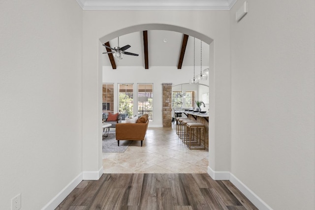 hall featuring arched walkways, baseboards, and wood finished floors