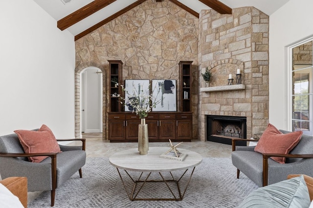 living area with beamed ceiling, a stone fireplace, and high vaulted ceiling