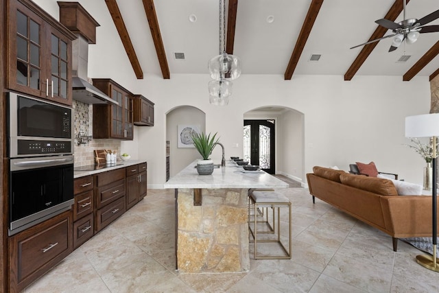 kitchen with black appliances, arched walkways, backsplash, a ceiling fan, and open floor plan