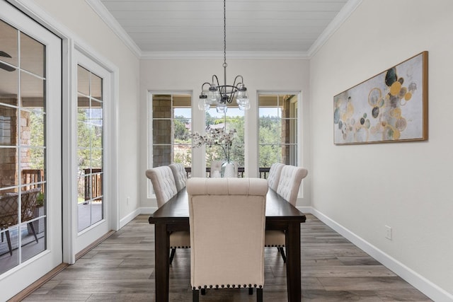 dining room featuring a chandelier, ornamental molding, wood finished floors, and baseboards