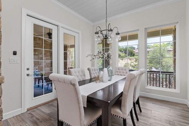 dining space with a chandelier, ornamental molding, baseboards, healthy amount of natural light, and wood finished floors