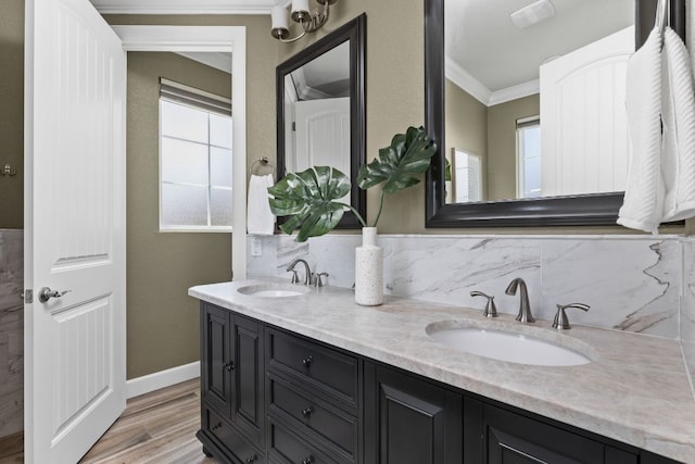 bathroom with crown molding, plenty of natural light, wood finished floors, tasteful backsplash, and double vanity