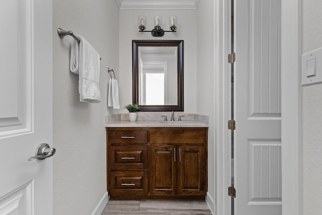 bathroom with vanity, ornamental molding, baseboards, and wood finished floors